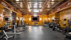 A gym with various exercise equipment, including treadmills and weight machines, and a large mirror on one wall.