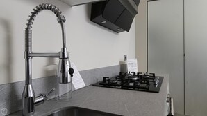 Uma cozinha com uma torneira moderna, um fogão a gás e um armário preto sobre o fogão.
