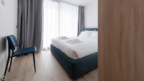 A hotel room with a bed, a chair, and a wooden door.