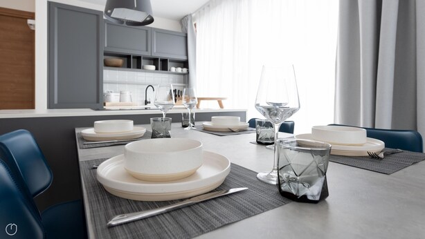 Un espace de salle à manger moderne avec une table dressée pour six personnes, comprenant assiettes, verres et couverts.