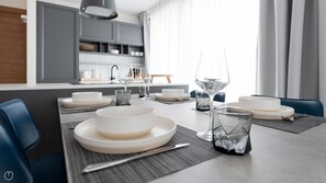 A modern dining area with a table set for six, including plates, glasses, and cutlery.