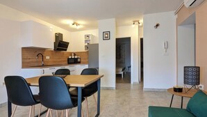 En kompakt bolig med tekøkken, spiseplads og et lille opholdsområde.