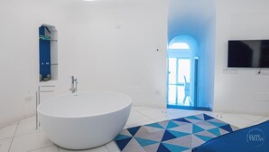 A modern bathroom with a large bathtub, a glass shower enclosure, and a blue-tiled floor. - Villa Blue Sea Amalfi (Ravello)
