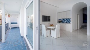A modern interior with a dining area, kitchen, and a glass door leading to a balcony. - Villa Blue Sea Amalfi (Ravello)