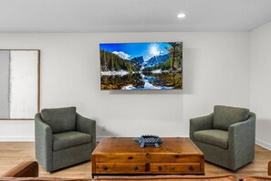 Relax in a serene space with a stunning landscape painting and comfortable seating area.
