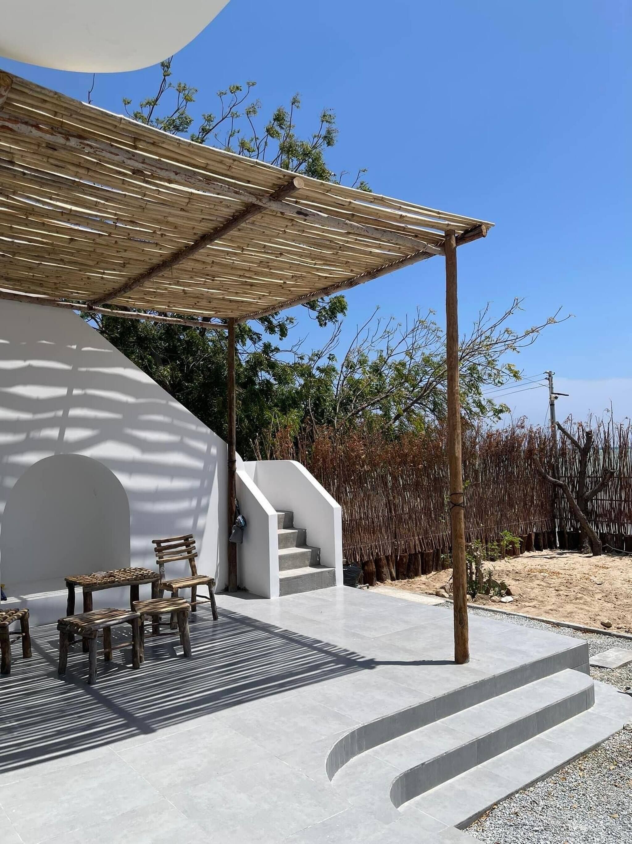 A modern outdoor seating area with a pergola, a staircase leading to a covered area, and a view of the surrounding landscape.