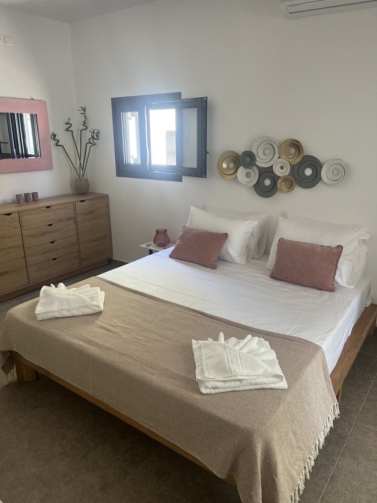 A bedroom with a bed, bedside tables, a dresser, a mirror, and wall decor.