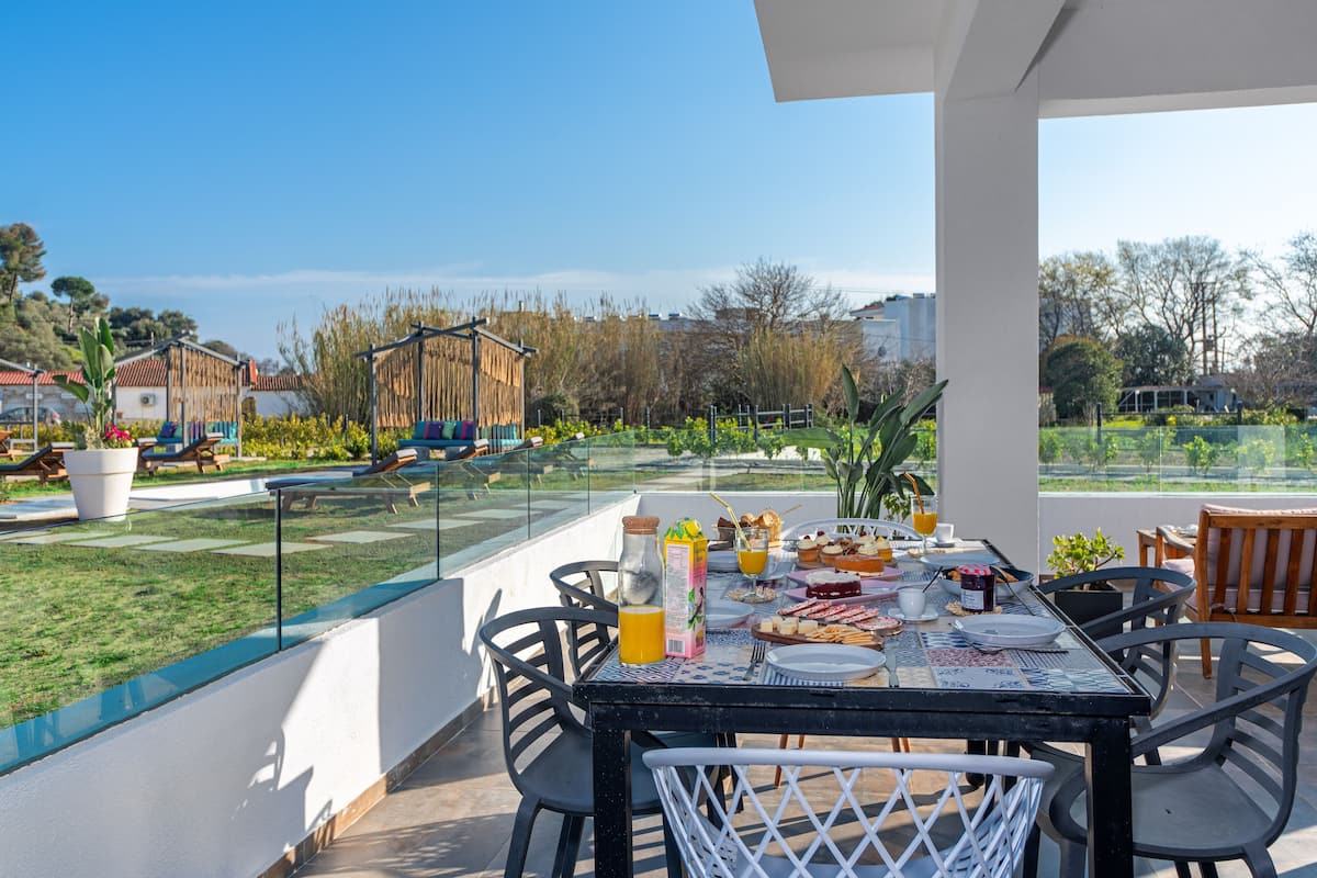 Un coin repas avec une table dressée pour le petit-déjeuner, des sièges à l’extérieur et une vue sur le paysage environnant.