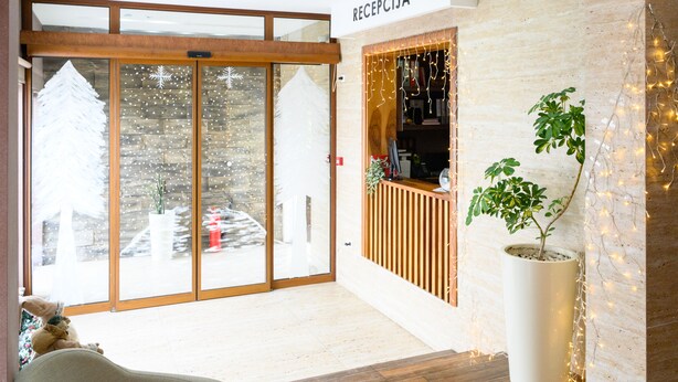 A reception area with a wooden reception desk, a potted plant, and a sign reading "RECEPCIJA". - Monogram (Inđija)