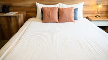 A neatly made bed with a wooden headboard, a bedside table with a lamp, and a telephone on the nightstand.