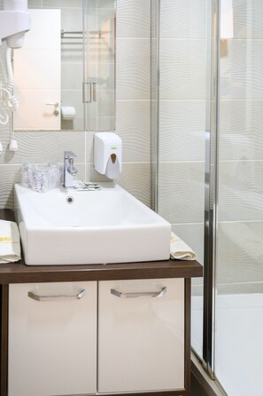 A bathroom with a white sink, a glass shower enclosure, and a mirror above the sink.