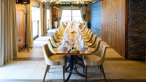 A long dining table set with chairs, a chandelier, and a view of the outdoors. - Monogram (Inđija)