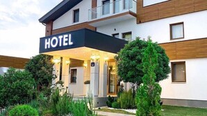 A hotel with a modern facade, a sign indicating it is a Monogram hotel, and a well-maintained garden area in front. - Monogram (Inđija)