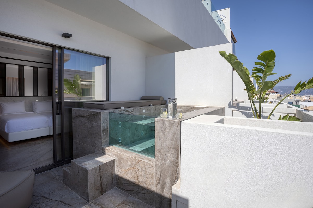Une salle de bain moderne avec un jacuzzi entouré de parois en verre, une baignoire blanche et une grande fenêtre donnant sur la ville.