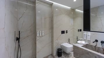 A modern bathroom with a glass-enclosed shower, a toilet, and a vanity with a mirror.
