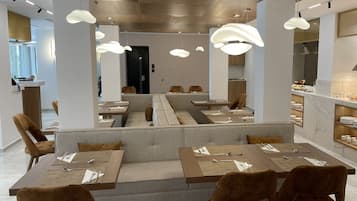 Ein modernes Restaurant mit einer zentralen Sitzgruppe, einzelnen Tischen und einer Bar.