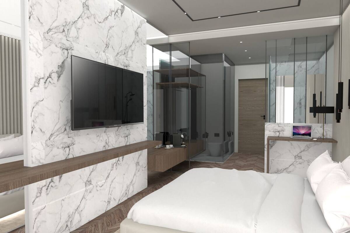 Une chambre moderne avec un grand lit, une télévision, une douche en verre et un bureau avec un ordinateur portable.