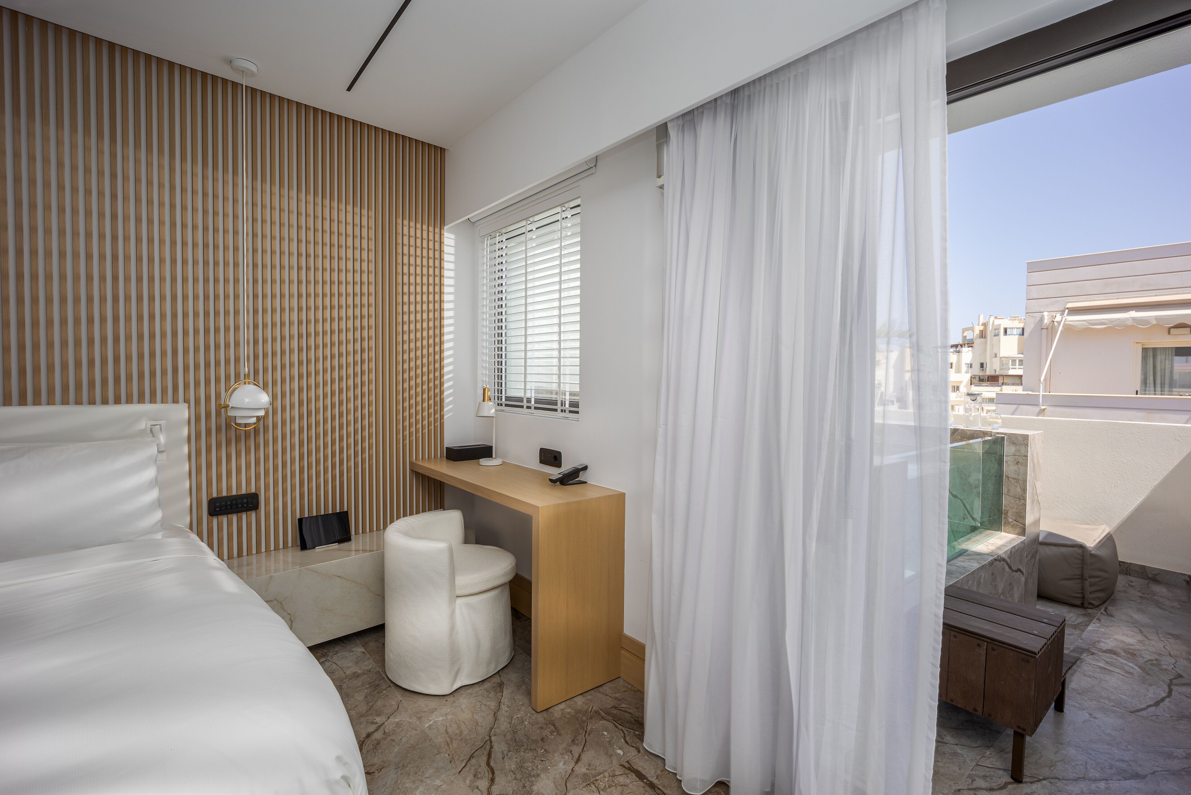 Ein modernes Hotelzimmer mit Bett, Schreibtisch, Stuhl und Blick auf die Stadt.