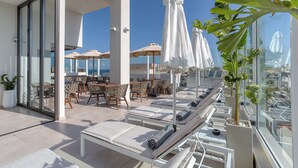 Une terrasse sur le toit équipée de chaises longues, de parasols et de mobilier de jardin pour prendre les repas.