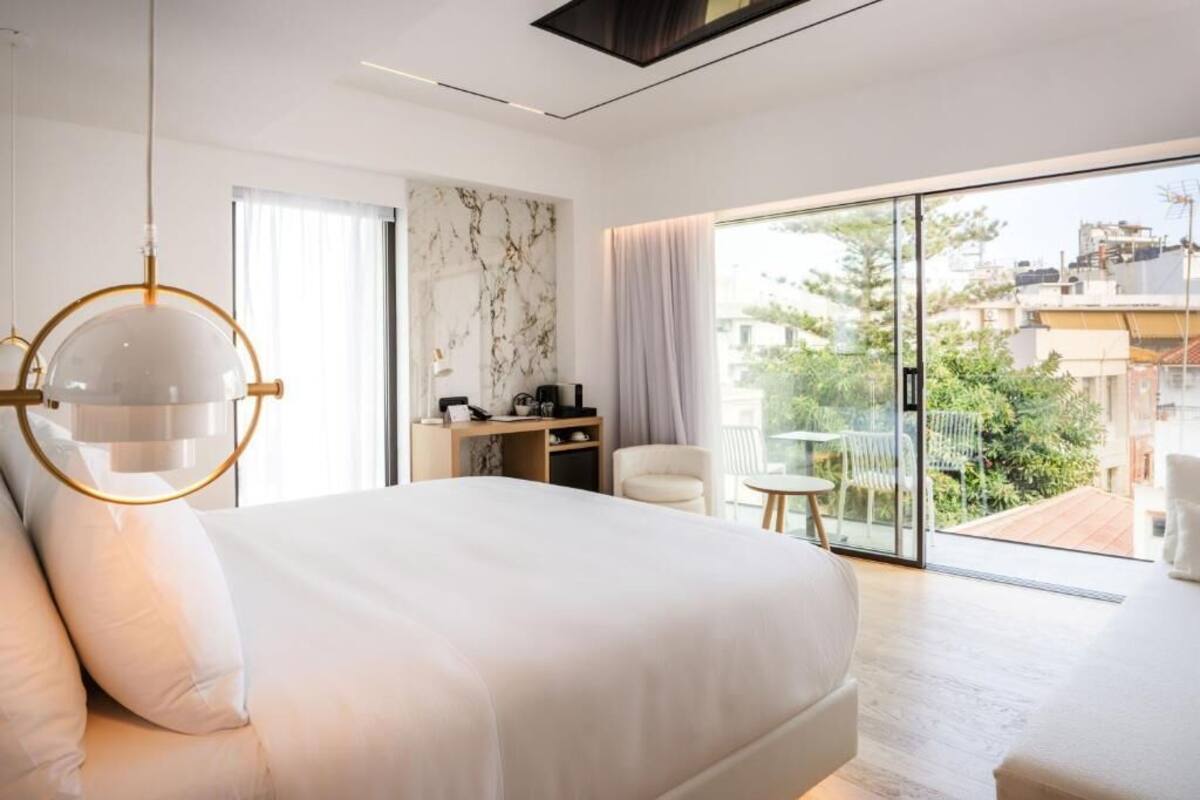 Une chambre moderne avec un grand lit, un bureau et un balcon offrant une vue sur la ville.