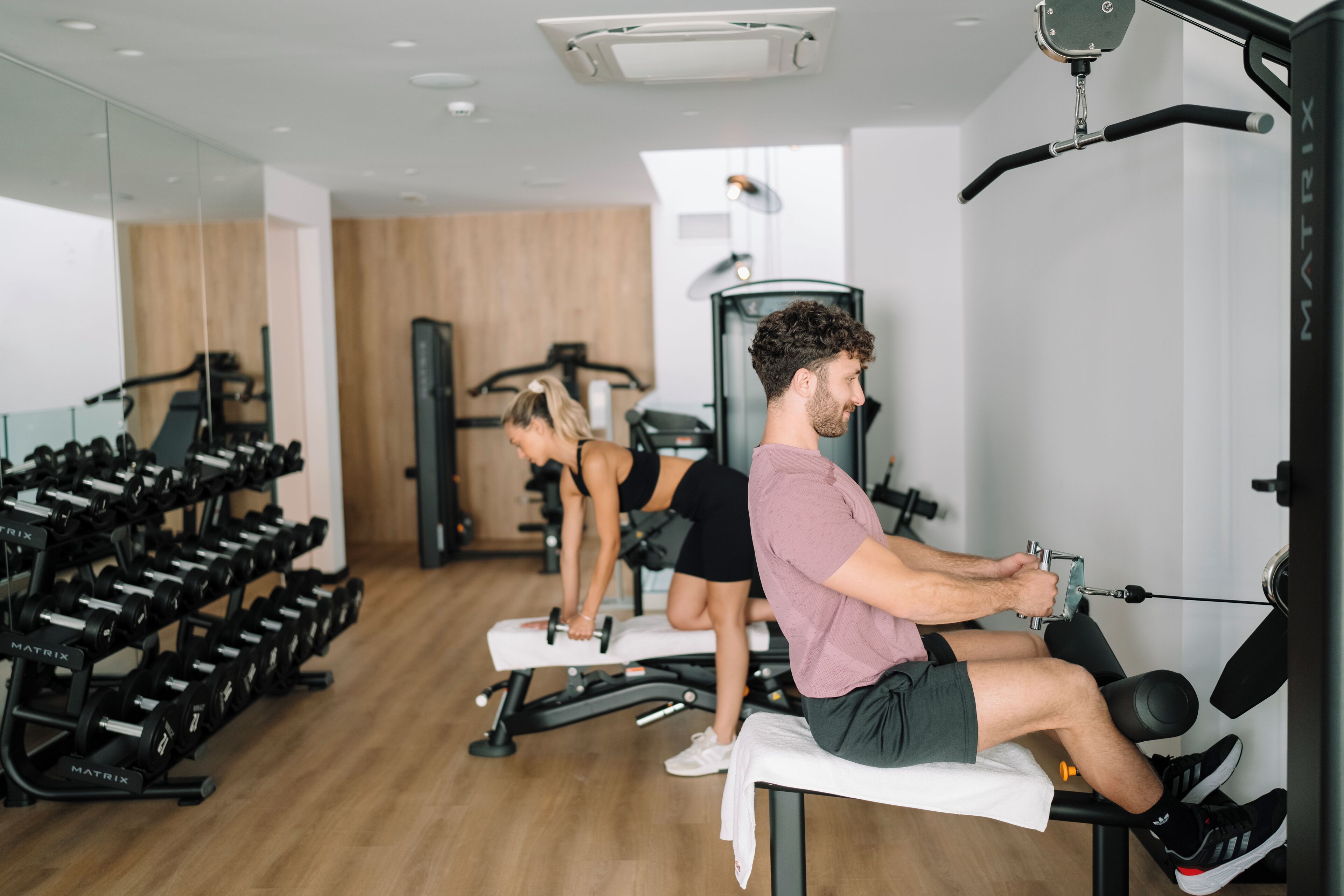 Una palestra con attrezzature da allenamento, tra cui manubri e un vogatore.