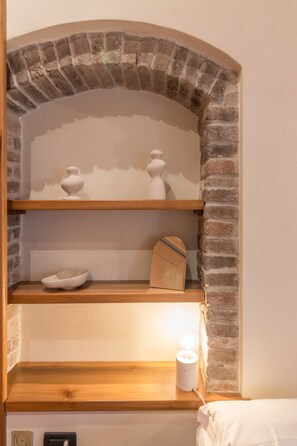 Una mensola con oggetti decorativi e una lampada in una stanza con pareti in mattoni.