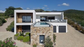 Een modern herenhuis met zwembad, een gevel van natuursteen en uitzicht op de omliggende heuvels.