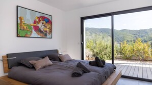 Een slaapkamer met een groot bed, een schilderij en uitzicht op de omgeving.