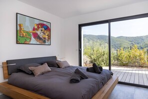 Une chambre avec un grand lit, un tableau et une vue sur l’extérieur.