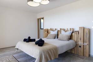 A modern bedroom with a wooden headboard, a bed with beige bedding, and a small bedside table. - VILLA GAIA- 5 bedrooms, swimming pool, sea view (Pietrosella)