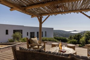 Une terrasse extérieure avec des meubles en bois, une table avec des verres et une vue sur un bâtiment moderne et un paysage urbain.