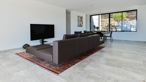 Una sala de estar moderna con un sofá seccional, un televisor de pantalla plana y un comedor con mesa y sillas.