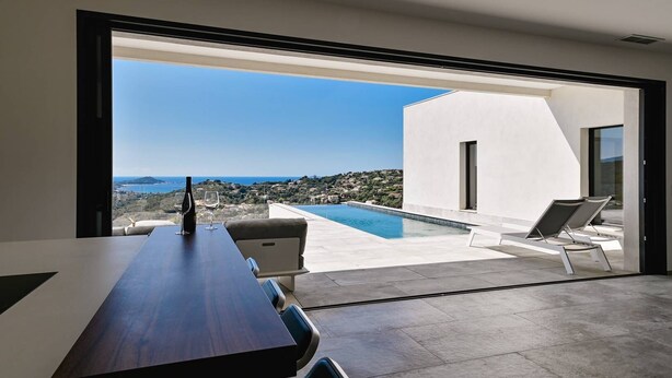 Un interior moderno con comedor, piscina y vista al mar.