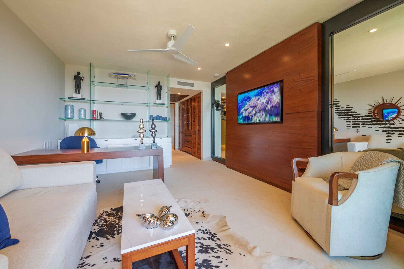 A modern living room with a sofa, coffee table, and a TV mounted on a wooden wall.