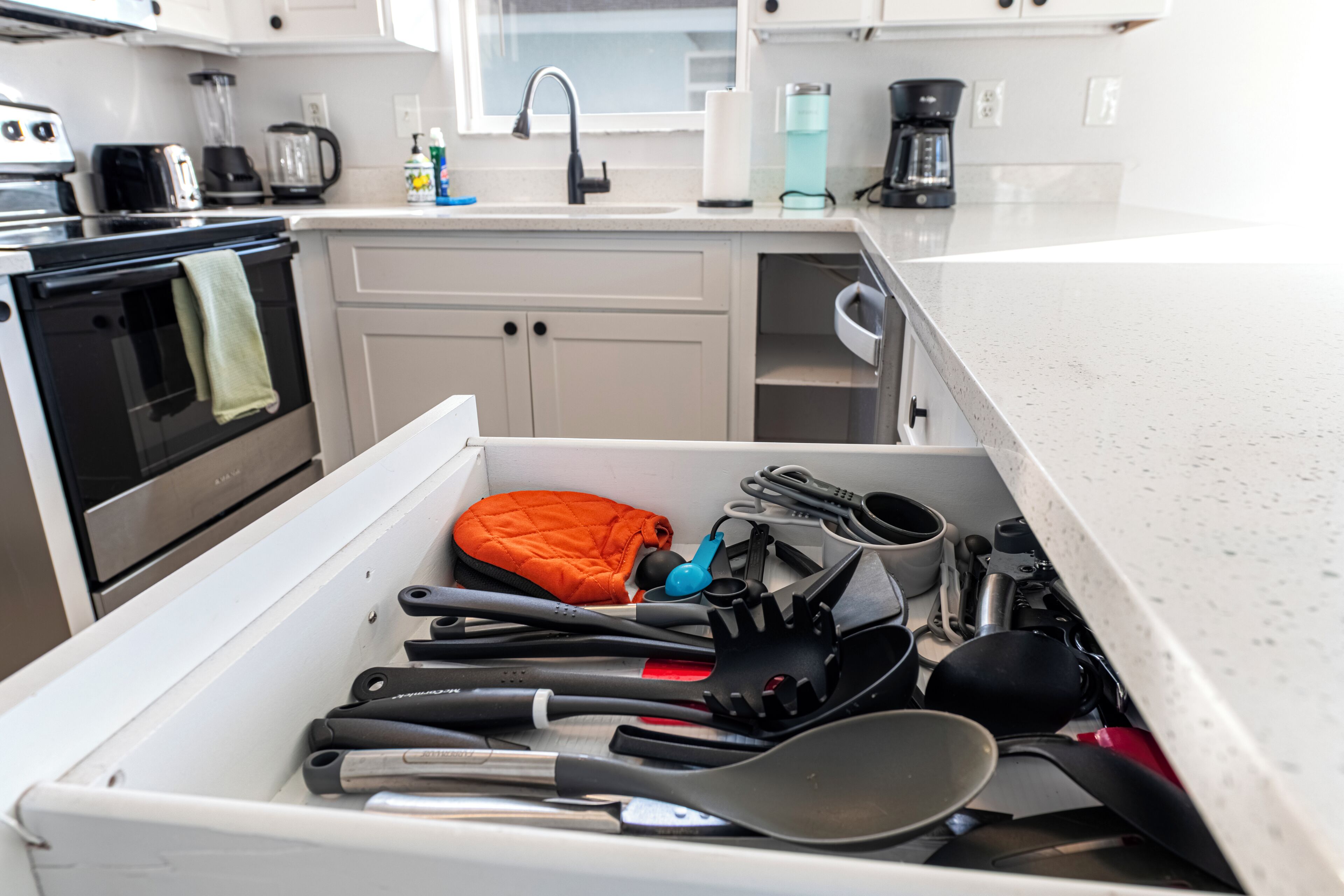 A kitchen with a white countertop, a sink, and a stove.