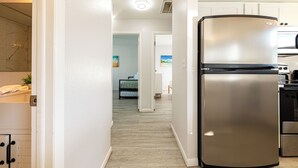 Une cuisine moderne dotée d’un réfrigérateur en acier inoxydable, de planchers en bois et d’armoires blanches.