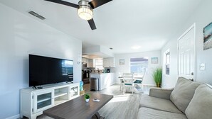 Un salon moderne avec un téléviseur à écran plat, une table basse en bois et un canapé beige.