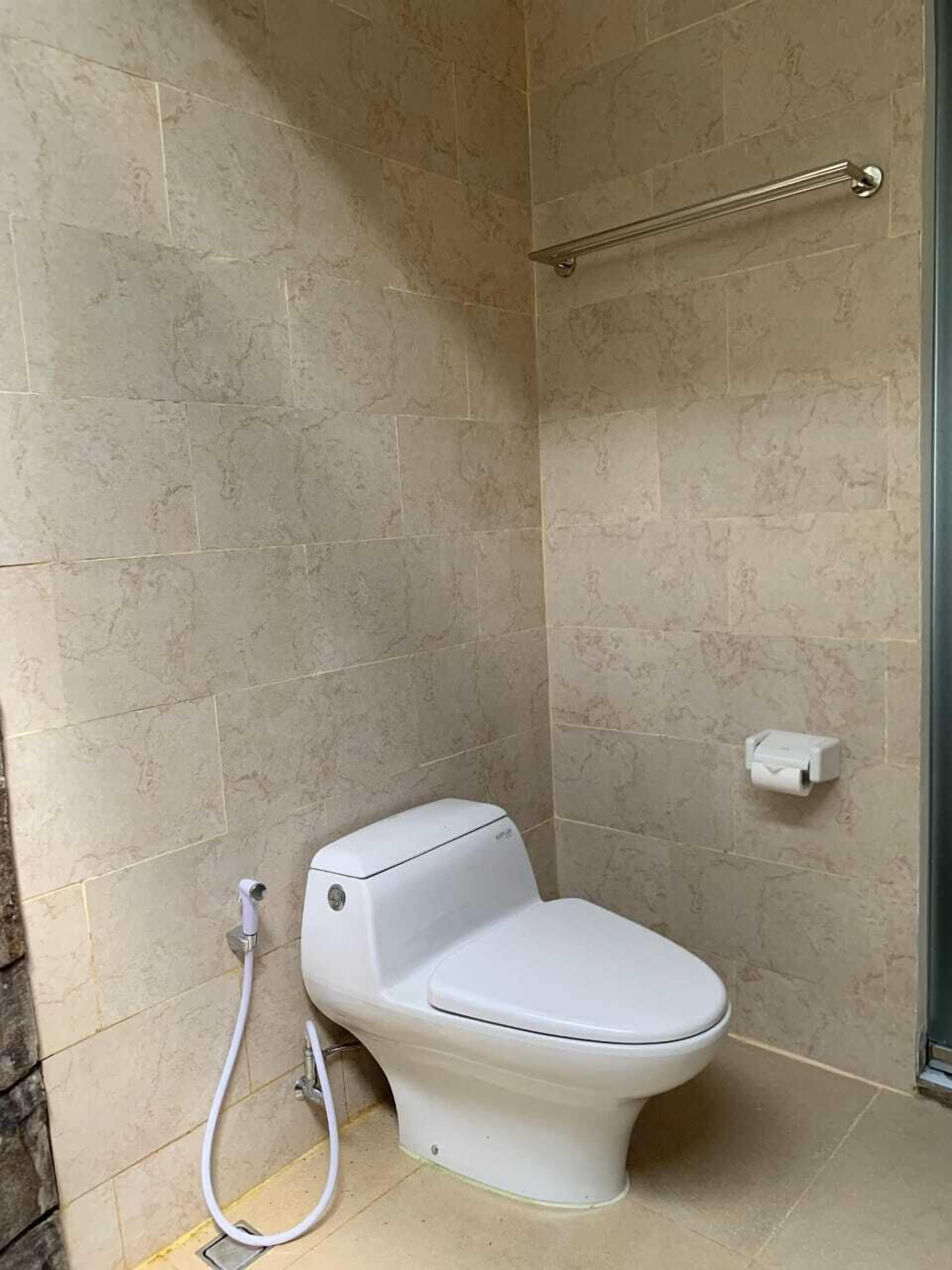 A bathroom with a toilet, a shower, and a toilet paper holder on the wall.