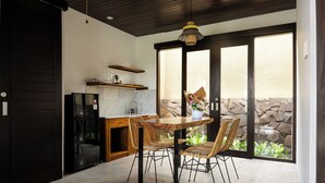 Una cocina moderna con comedor, que incluye una mesa y sillas de madera, un refrigerador empotrado y una pared de piedra al exterior.