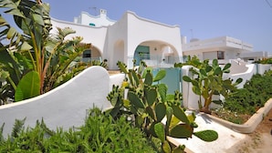 A white building with a blue door and arches, surrounded by cacti and other plants. - 3241 Villa Esador by Barbarhouse (Racale)