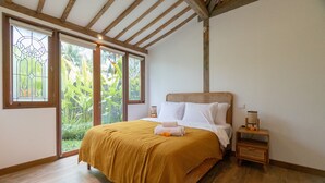 A bedroom with a large bed, wooden headboard, and a nightstand with a lamp. - Singgah di Ubud 1 (Ubud)
