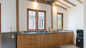 A kitchen with wooden cabinets, a black refrigerator, and a built-in stove. - Singgah di Ubud 1 (Ubud)