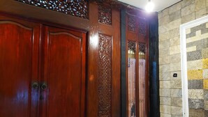 A room with a wooden wardrobe, a bench, and a tiled wall. - Dewi House Pondok Hijau Parongpong Bandung 1 (Parongpong)