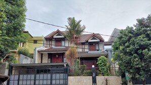 A residential building with a gated entrance, a balcony, and a small garden area. - Dewi House Pondok Hijau Parongpong Bandung 1 (Parongpong)