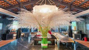 A lobby with a central reception desk, a large chandelier, and a decorative plant arrangement. - Hoi An Town Home Resort (Da Nang)