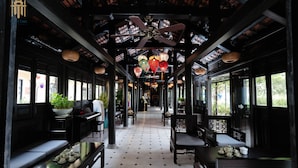 A traditional-style corridor with seating areas, ceiling fans, and hanging lanterns. - Hoi An Town Home Resort (Da Nang)