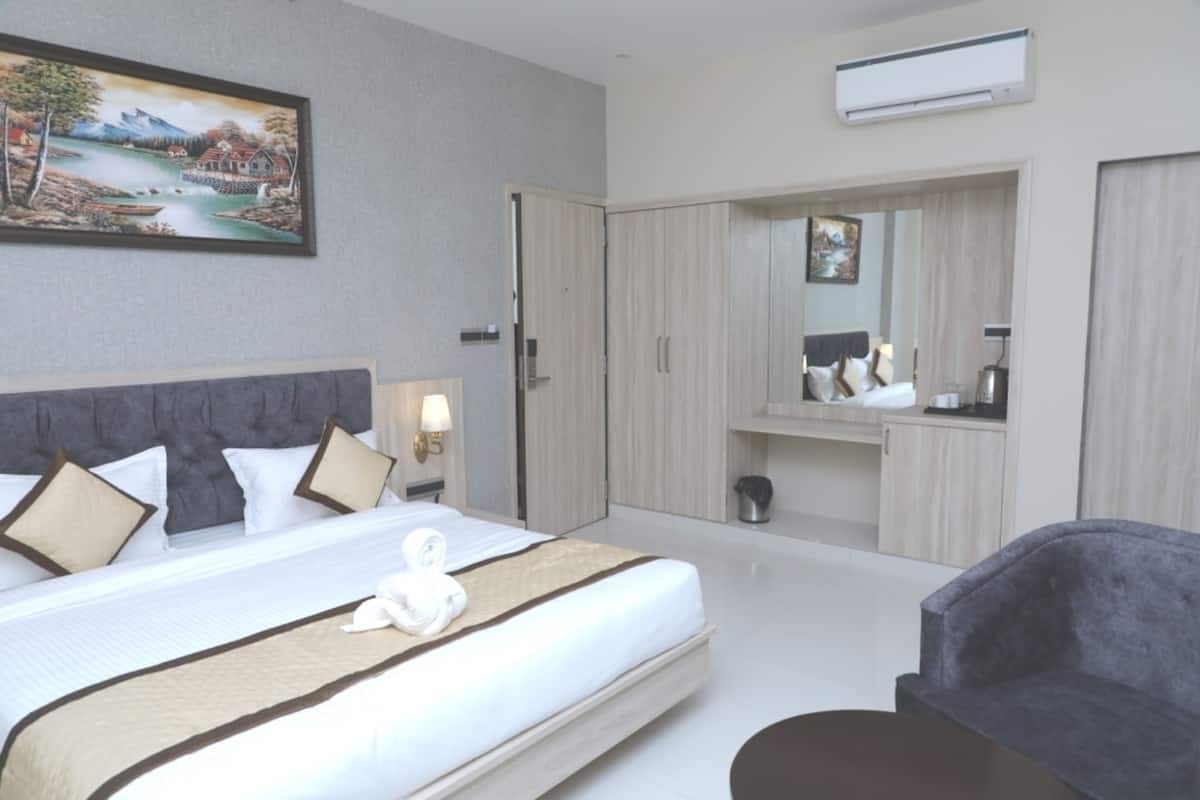 A hotel room with a large bed, a wardrobe, a mirror, and a desk.