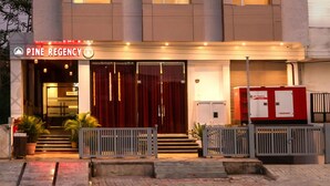 A modern hotel named Pine Regency with a prominent entrance, large windows, and a well-lit facade. - Pine Regency - Aravali's Peak view (Udaipur)