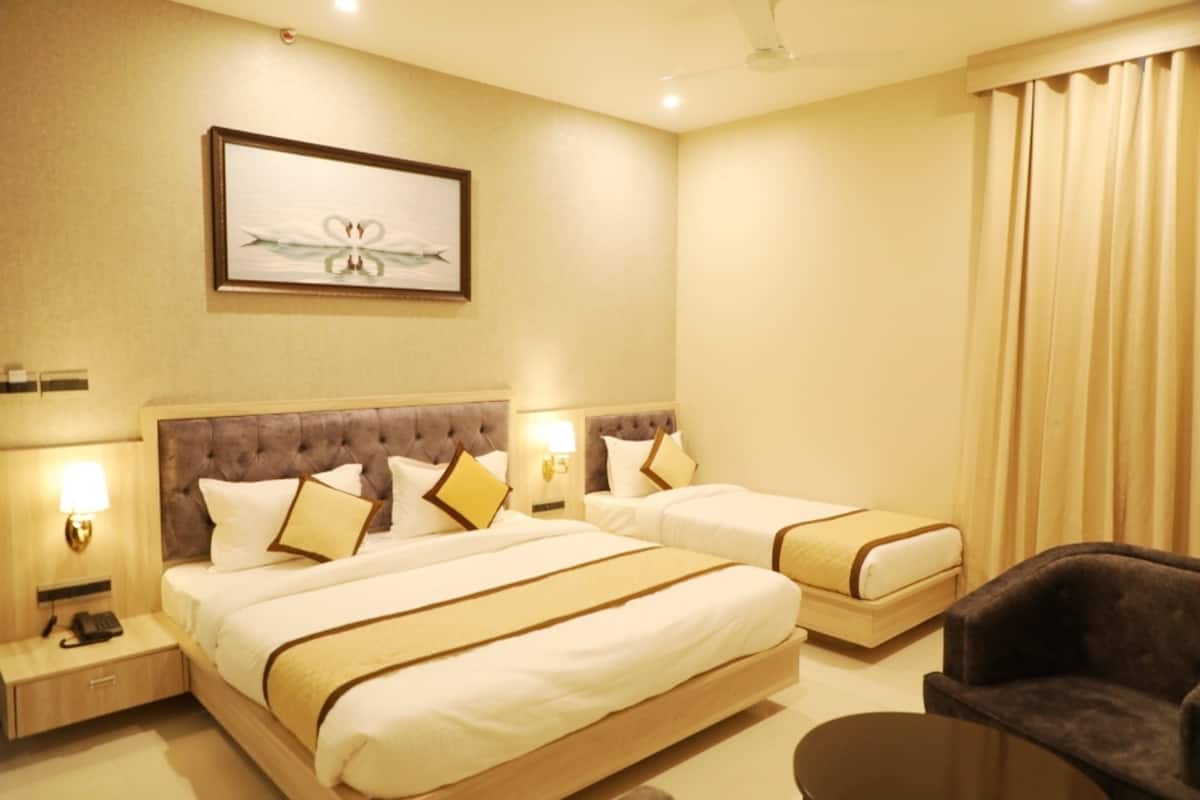 A hotel room with two beds, a large window with curtains, a small table, and a framed picture on the wall.