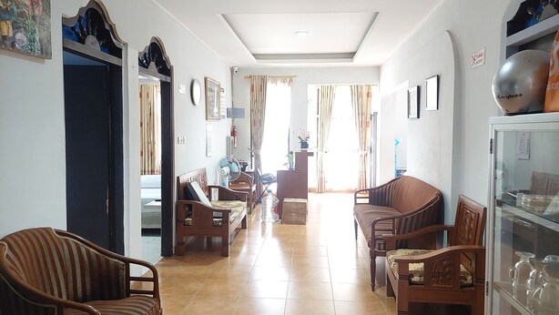 A spacious living room with a tiled floor, wooden furniture, and a glass display cabinet. - Pondok Seruni Kemanggisan Jakarta (Jakarta)